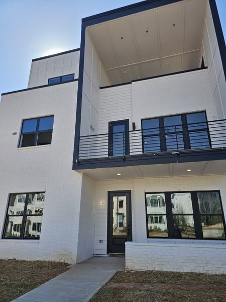 A sleek modern home with large windows and a balcony in The Gathering – Alpharetta by Brock Built (Alpharetta, GA).