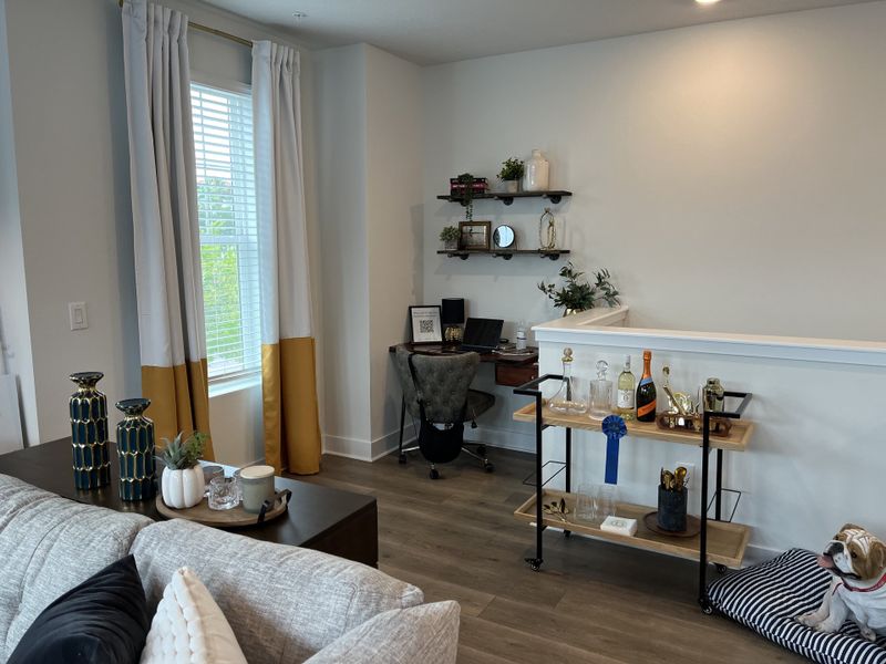 A cozy home office nook with natural light, modern decor, and a stylish bar cart in the corner.