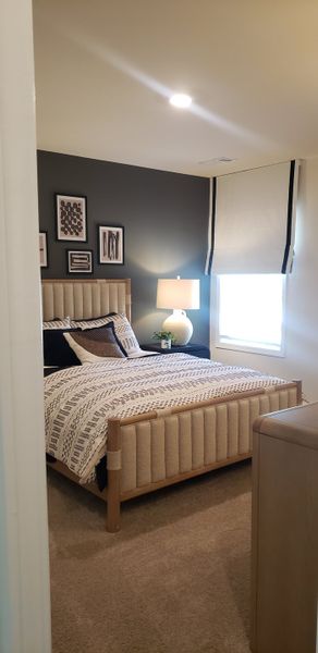 Cozy bedroom with a cushioned bed frame, patterned bedding, and soft lighting, accentuated by modern wall art.