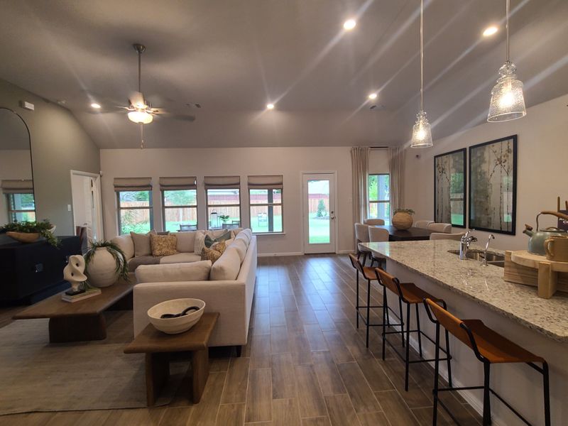 A spacious open-concept living area with a large sectional, elegant lighting, and a sleek kitchen island with modern barstools. A spacious open-concept living area with a large sectional, elegant lighting, and a sleek kitchen island with modern barstools.