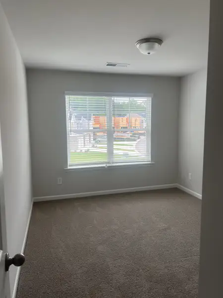 A bright, carpeted room with a large window and neutral walls, offering a cozy, inviting space. A bright, carpeted room with a large window and neutral walls, offering a cozy, inviting space.