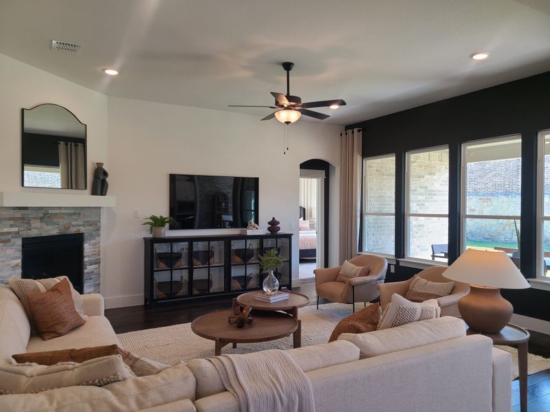 A cozy living room featuring a stone fireplace, plush seating, and large windows bringing in natural light. A cozy living room featuring a stone fireplace, plush seating, and large windows bringing in natural light.