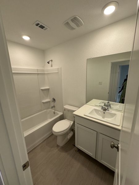 A sleek bathroom with a white vanity, bathtub, and soft lighting, offering a clean, modern aesthetic.