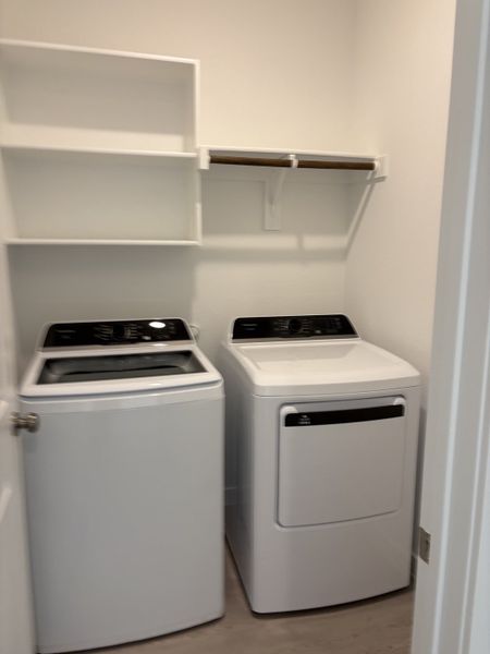 A functional laundry room with modern washer and dryer, open shelving, and clean design.