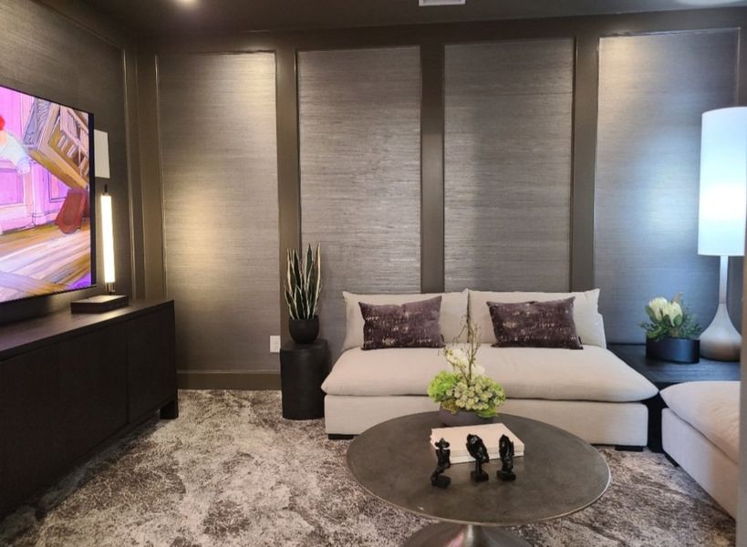 A cozy living area with a plush sectional sofa, textured walls, a round coffee table, and ambient lighting.