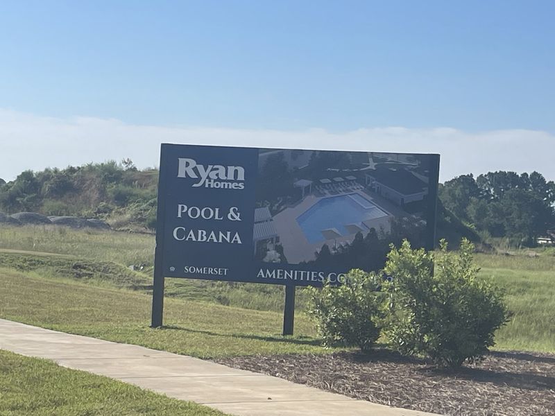 A welcoming sign for the pool and cabana at Somerset Two-Story Homes by Ryan Homes in Santee, SC, with green surroundings.
