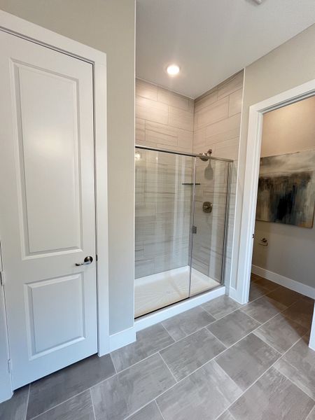 A modern bathroom with a sleek glass shower, elegant gray tile flooring, and neutral wall tones.