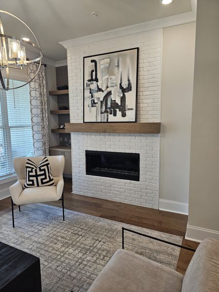 A cozy living area with an elegant fireplace, abstract art, and plush seating, illuminated by chic pendant lighting.