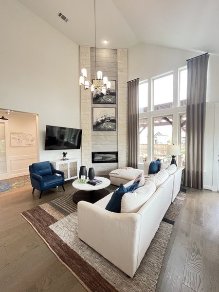 A bright, elegant living room with high ceilings, cozy seating, a fireplace, and stylish decor.