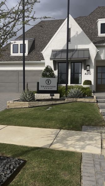 A beautiful white brick home with manicured landscaping in Mustang Lakes – 86’ by Tradition Homes (Celina, TX).