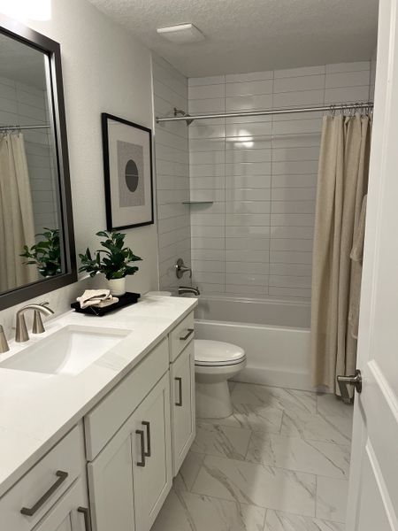 A chic bathroom featuring white cabinetry, a sleek sink, and elegant tiling with contemporary decor and lighting.