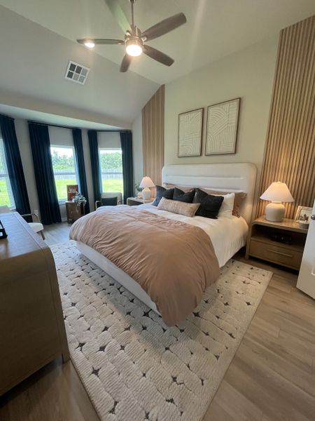A cozy bedroom with a plush bed, modern artwork, and ample natural light through large windows. A cozy bedroom with a plush bed, modern artwork, and ample natural light through large windows.