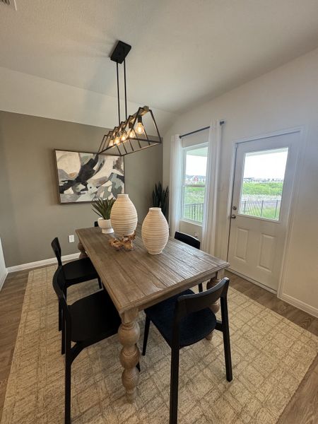 A cozy dining area with a rustic wooden table, modern lighting, and contemporary artwork, offering a warm and inviting atmosphere. A cozy dining area with a rustic wooden table, modern lighting, and contemporary artwork, offering a warm and inviting atmosphere.