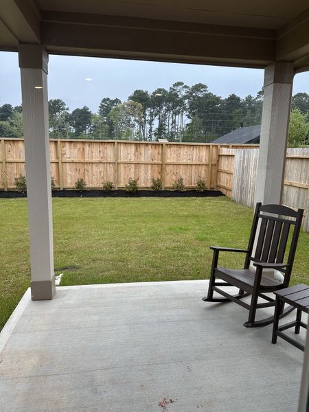 A cozy patio with a wooden rocking chair and a spacious fenced backyard view, perfect for relaxation. A cozy patio with a wooden rocking chair and a spacious fenced backyard view, perfect for relaxation.