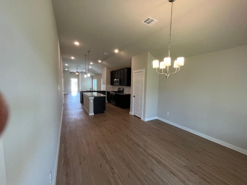 An open-concept interior with wood floors, modern lighting, and a sleek kitchen featuring dark cabinetry and an island.