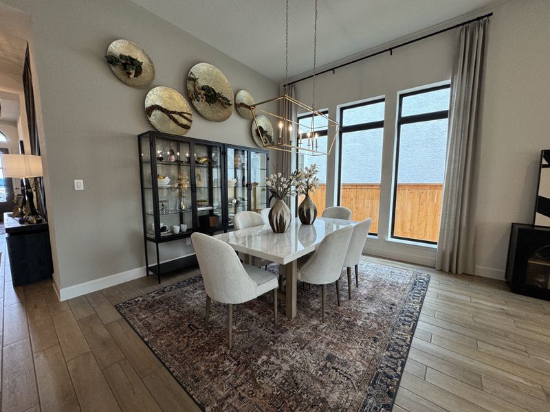 A modern dining room with elegant decor, featuring a marble table, plush chairs, and wall art in a well-lit space.