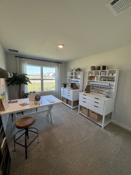 A bright home office with large windows, white furniture, and ample storage, perfect for creative projects and productivity.