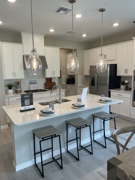 A modern kitchen featuring sleek white cabinets, stainless steel appliances, and elegant pendant lighting over an island. A modern kitchen featuring sleek white cabinets, stainless steel appliances, and elegant pendant lighting over an island.