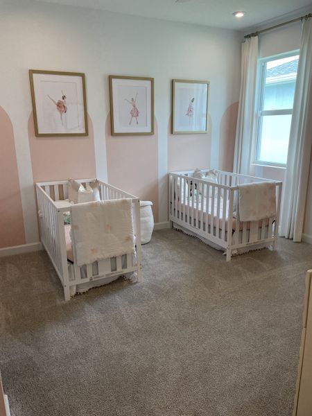 A charming nursery with twin white cribs, plush carpeting, and elegant ballet-themed décor. A charming nursery with twin white cribs, plush carpeting, and elegant ballet-themed décor.