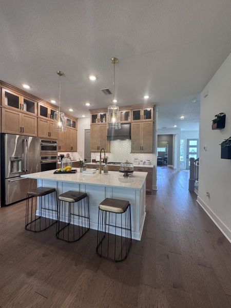 A modern kitchen featuring a spacious island, elegant pendant lights, and warm wood cabinets for a stylish look.