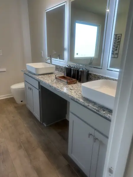 A modern bathroom with dual vessel sinks, granite countertops, and sleek wooden flooring. A modern bathroom with dual vessel sinks, granite countertops, and sleek wooden flooring.