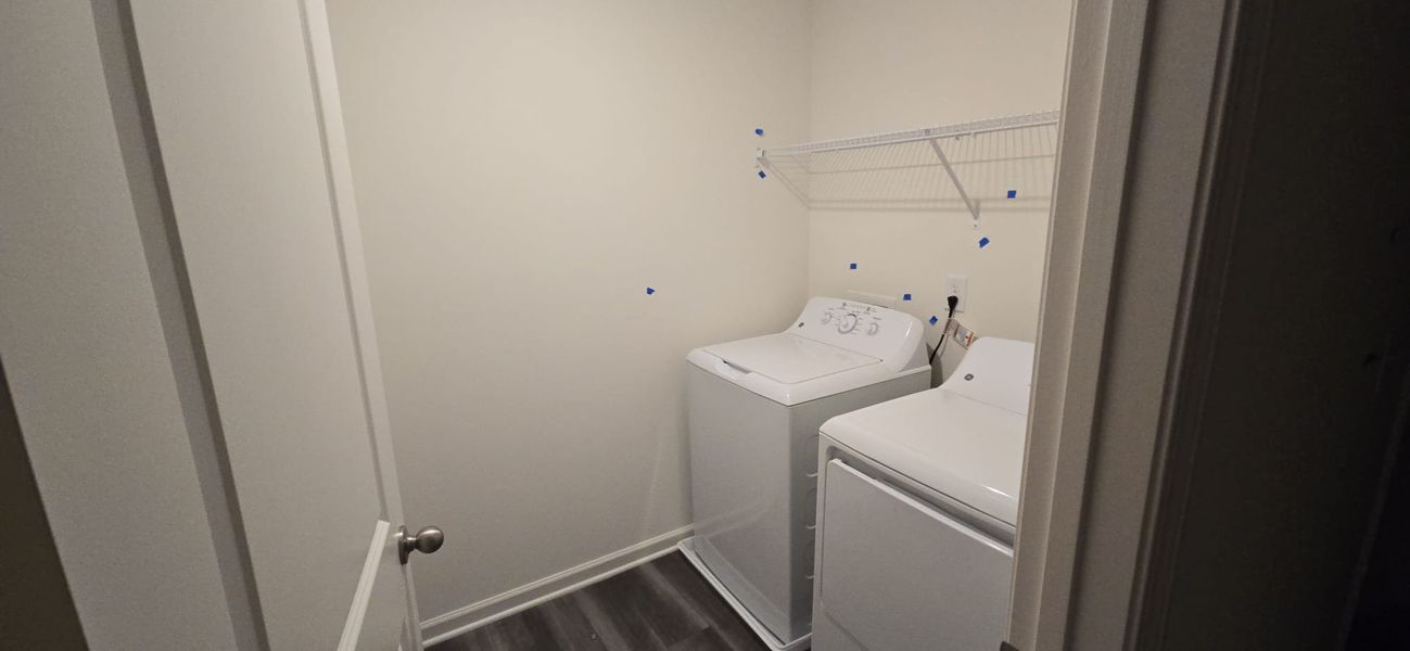A functional laundry room featuring a washer, dryer, and overhead shelving for convenience.