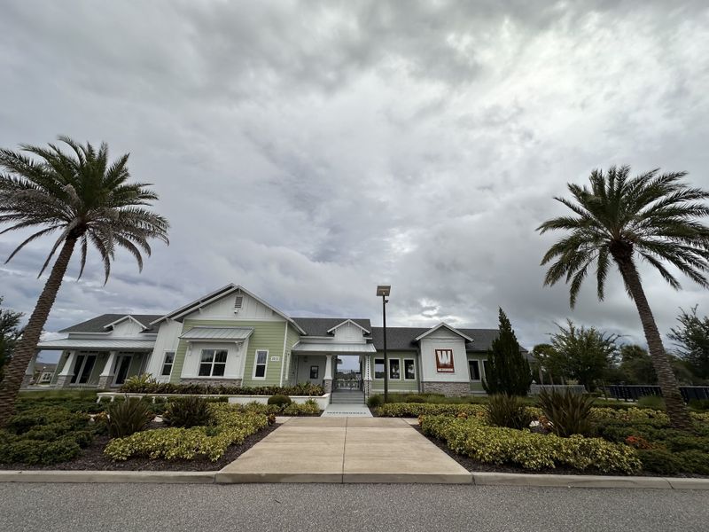 A charming clubhouse with lush landscaping and palm trees in Waterbrooke by Mattamy Homes (Clermont, FL).