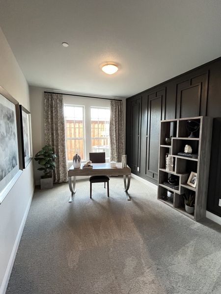 A chic home office with dark accent wall, elegant shelving, large windows, and plush carpeting, creating a refined workspace. A chic home office with dark accent wall, elegant shelving, large windows, and plush carpeting, creating a refined workspace.