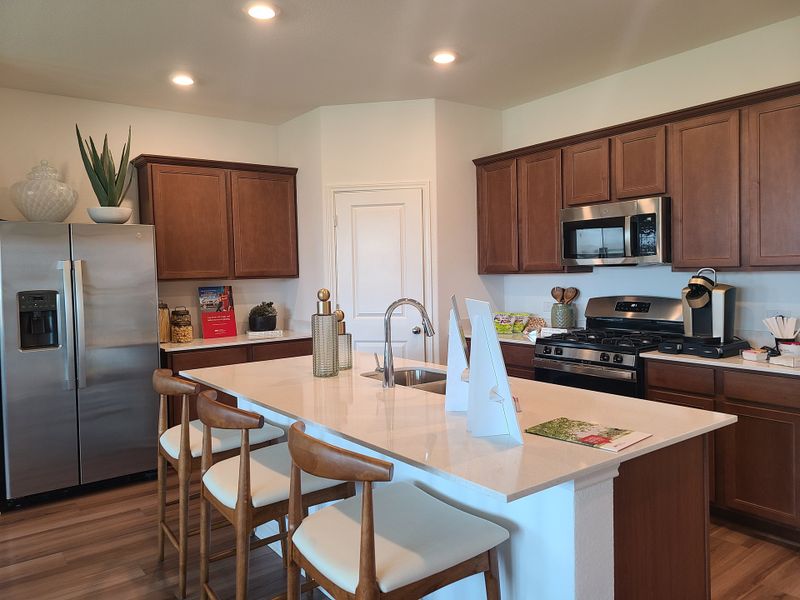 A modern kitchen with wooden cabinets, stainless steel appliances, and a spacious island with seating.