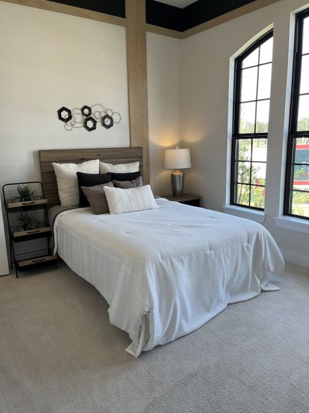 A cozy bedroom with a wooden headboard, plush pillows, and a large window providing ample natural light.