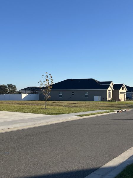 A modern home with a spacious lawn and a sleek design in Otter Woods Estates by Highland Homes of Florida (Auburndale, FL).