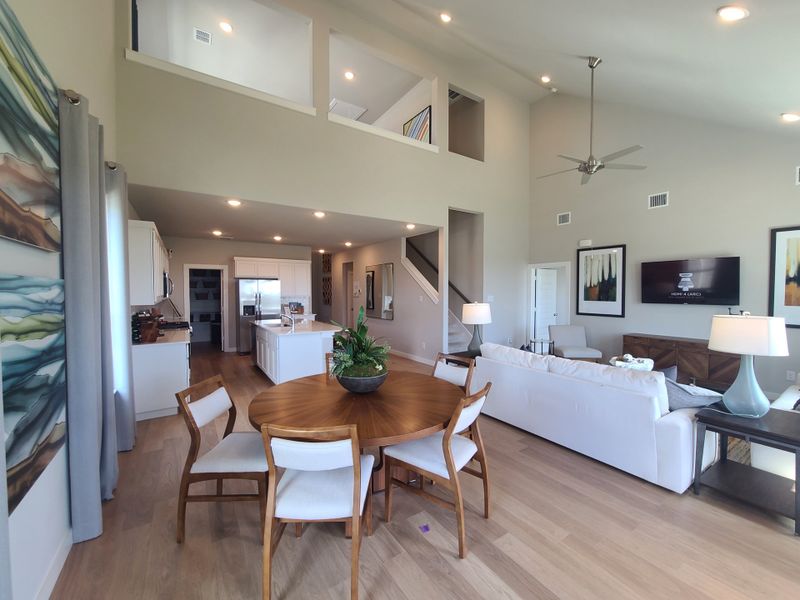 An open-concept living area with modern furnishings, high ceilings, and a sleek kitchen with an island and dining nook. An open-concept living area with modern furnishings, high ceilings, and a sleek kitchen with an island and dining nook.