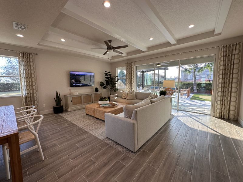 A bright and open-concept living space with wood flooring, modern furniture, and elegant finishes in Crossroads at Kelly Park by Dream Finders Homes (Apopka, FL).