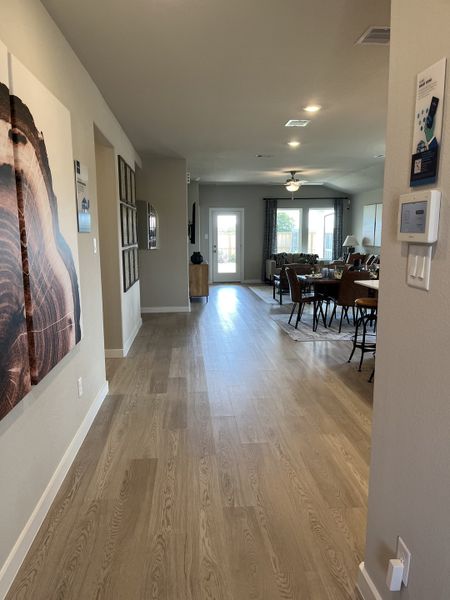 A welcoming hallway with wood flooring, modern art, and an open living area leading to a bright patio view.
