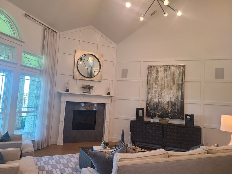 A sophisticated living room featuring high ceilings, stylish lighting, and a modern fireplace with tasteful decor.