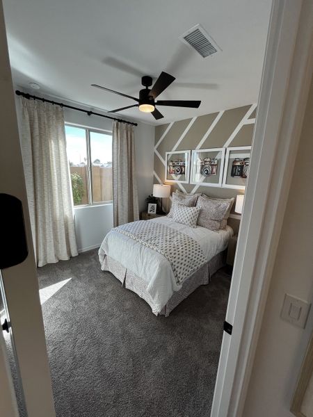 Stylish bedroom with a modern accent wall, soft lighting, and a large window bringing in natural daylight.