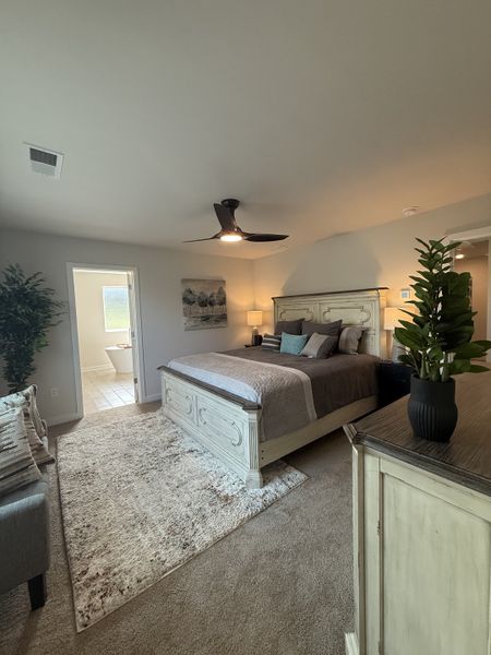 A cozy bedroom featuring a stylish bed, soothing neutral tones, plush carpet, and a modern ceiling fan. A cozy bedroom featuring a stylish bed, soothing neutral tones, plush carpet, and a modern ceiling fan.