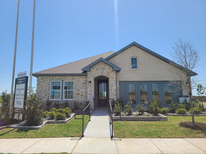 A charming stone-brick home with lush landscaping at Brookshire at Legacy Hills-60s by Ashton Woods, Celina, TX.