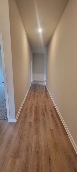 A sleek hallway featuring wood-style flooring and soft lighting, offering a warm and inviting entrance to the home.