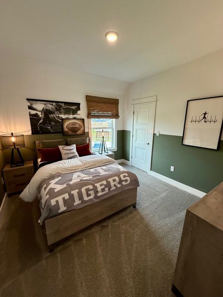A cozy bedroom with sports-themed decor, featuring a football poster and stylish bedding, perfect for relaxation.