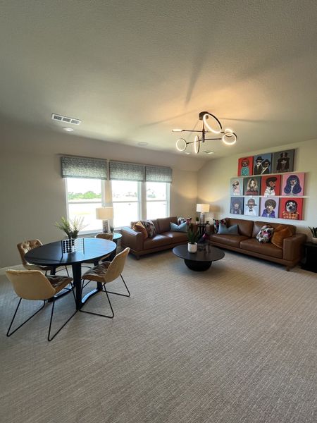 A cozy living room with a modern chandelier, leather sofas, and a round dining table, accentuated by vibrant artwork. A cozy living room with a modern chandelier, leather sofas, and a round dining table, accentuated by vibrant artwork.