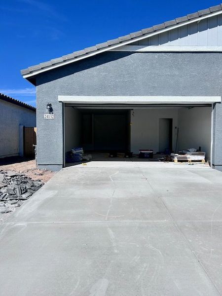 A modern gray garage and driveway under clear skies in Agave Trails by Ashton Woods (Buckeye, AZ).