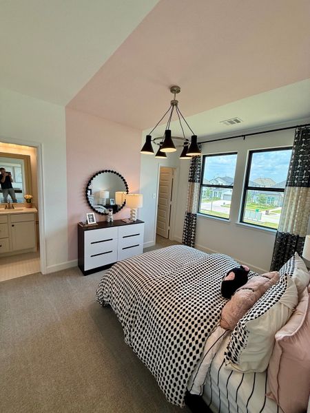 Cozy bedroom featuring polka dot bedding, elegant chandelier, and scenic windows with modern curtains.