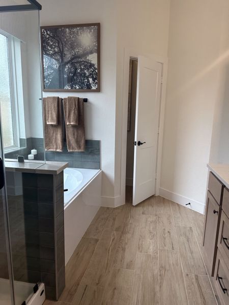 A serene bathroom featuring a freestanding tub, wood-look tile flooring, and a large window with natural light. A serene bathroom featuring a freestanding tub, wood-look tile flooring, and a large window with natural light.