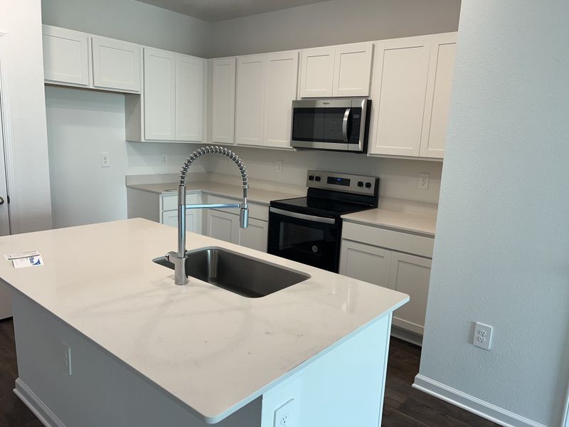 A modern kitchen featuring sleek white cabinets, stainless steel appliances, and a stylish island with a high-arc faucet. A modern kitchen featuring sleek white cabinets, stainless steel appliances, and a stylish island with a high-arc faucet.
