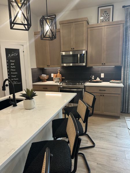 A modern kitchen with sleek cabinetry, pendant lighting, and a spacious island with stylish seating. A modern kitchen with sleek cabinetry, pendant lighting, and a spacious island with stylish seating.