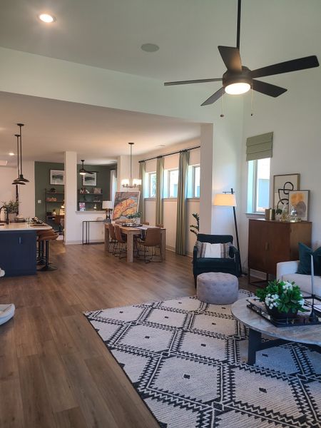 An open-concept living area with stylish decor, wood floors, a cozy rug, and modern lighting, perfect for entertaining.
