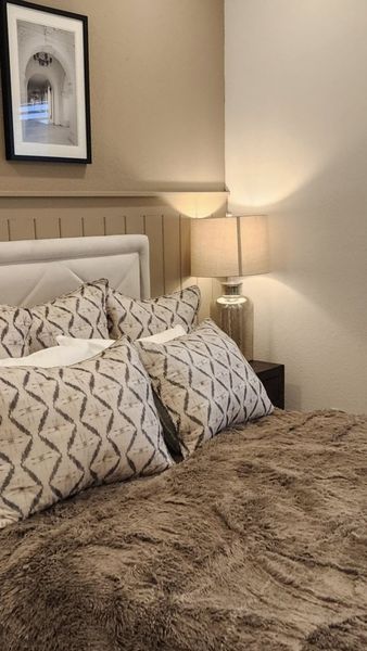 A cozy bedroom with a plush fur bedspread, neutral tones, and elegant framed artwork for a warm and inviting atmosphere.