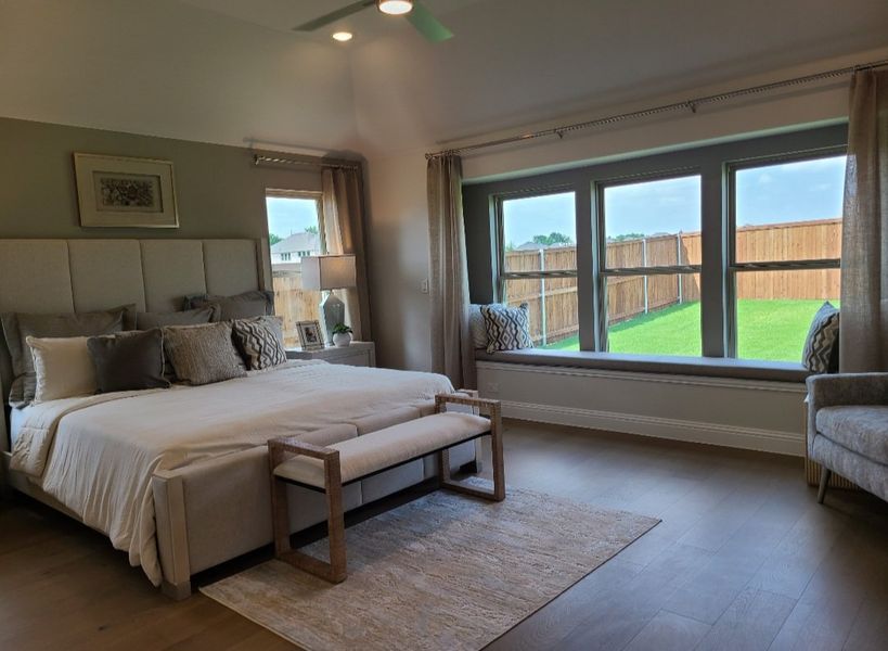 A cozy bedroom with large windows, elegant bedding, and a comfortable sitting area, overlooking a fenced backyard. A cozy bedroom with large windows, elegant bedding, and a comfortable sitting area, overlooking a fenced backyard.