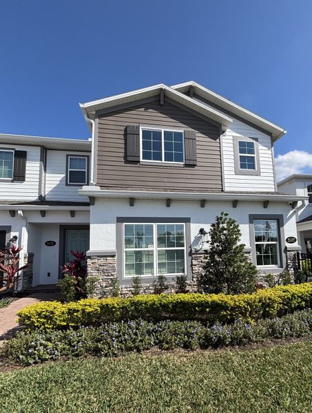 A beautiful sales center with a charming exterior and lush greenery in Eden at Crossprairie by M/I Homes (St. Cloud, FL).